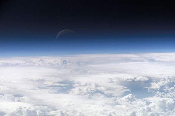 地球的大氣層與遠方的新月。圖／wiki
